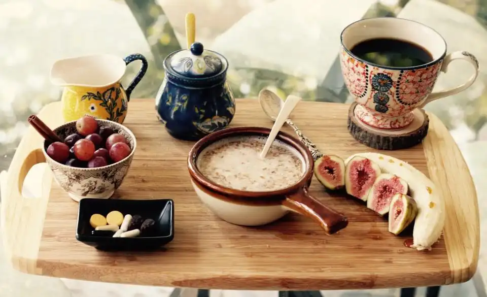 Bandeja de madeira com frutas, banana, mingau e bule de café